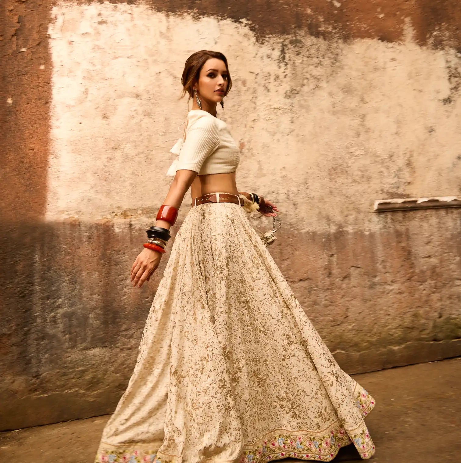 A flowing cream-colored lehenga skirt with delicate embroidery paired with a cropped white blouse.